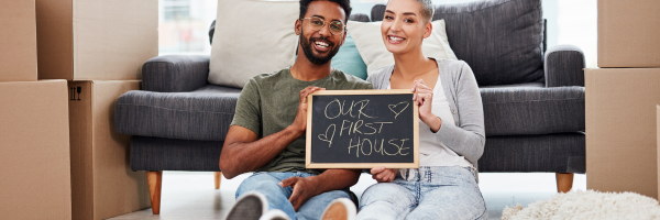 First home buyers smiling with board